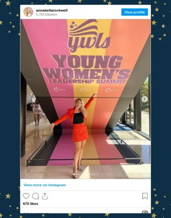 Annabella Rockwell in front of the Young Women's Leadership Summit Banner