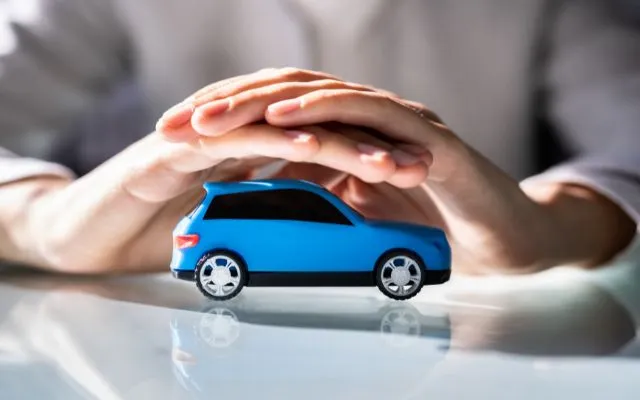 Hands Protecting a Car Symbolizing Car Insurance